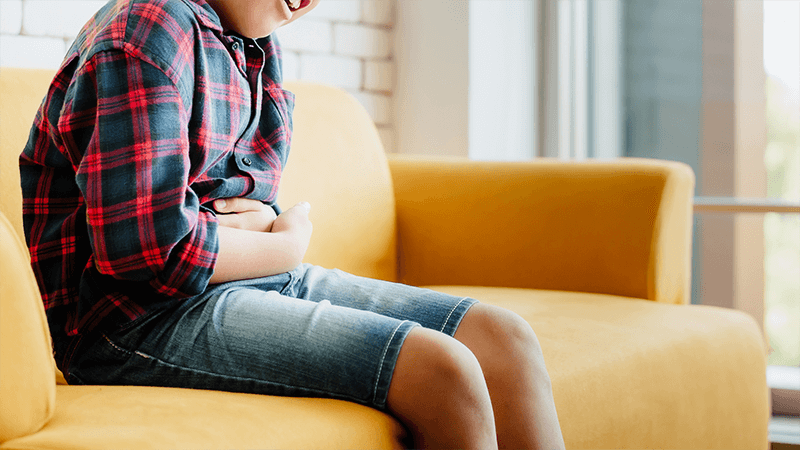 Child experiencing stomach pain, a potential sign of peptic ulcer, treated by Dr. Mona Dave, a pediatric gastroenterologist in Frisco, Texas.